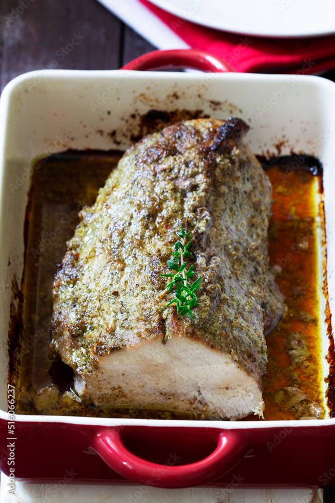 Pork loin baked with herbs, served in a baking dish. Rustic style.