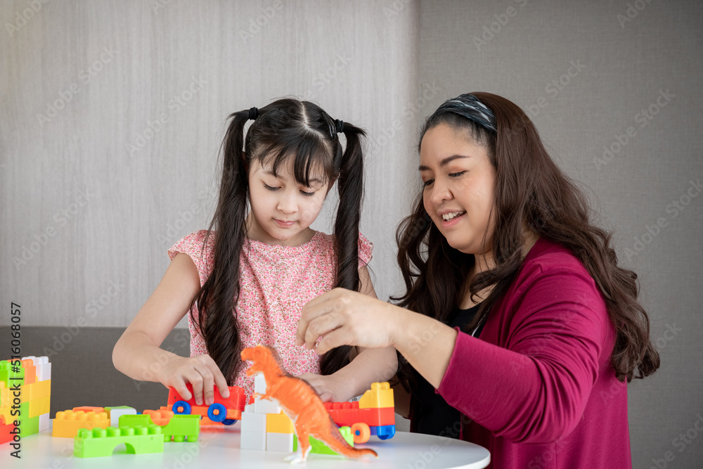 Fototapeta premium Young mother playing toy with daughter in a home., Happy and relaxing time.