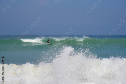 Un surfeur en combinaison glisse sur une vague