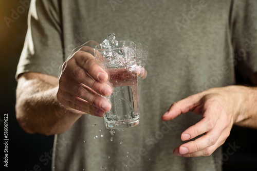A man holds a glass of water with a shaking hand. The concept of parkinson's disease and tremor. photo