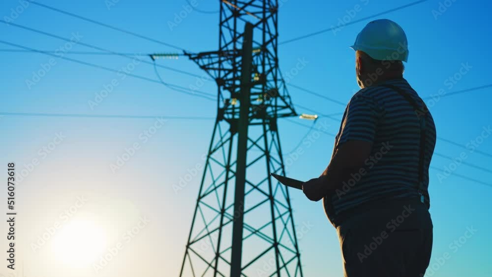 Silhouette businessman man in protective helmet in field using tablet and looks at telecommunications tower. Construction worker stands against blue sky. Online work with technology for connection. Silhouette businessman man in protective helmet in field using tablet and looks at telecommunications tower. Construction worker stands against blue sky. Online work with technology for connection.