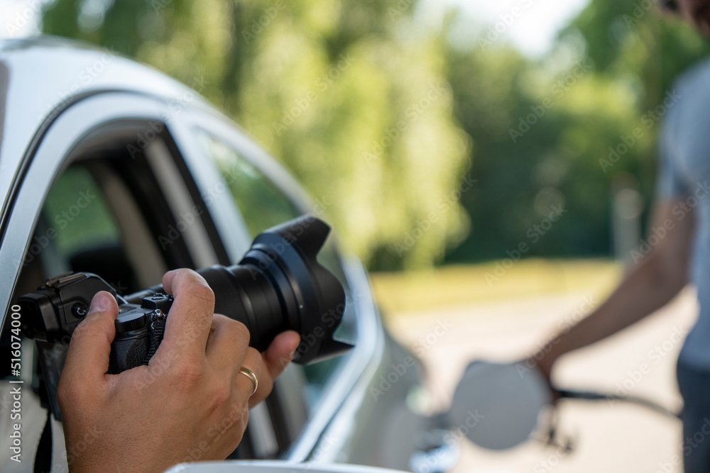 A paparazzi sits in his car and takes pictures of a famous person. Spy with camera in the car. A private detective, sitting inside the car, taking pictures with the camera. A paparazzi sits in his car and takes pictures of a famous person. Spy with camera in the car. A private detective, sitting inside the car, taking pictures with the camera.