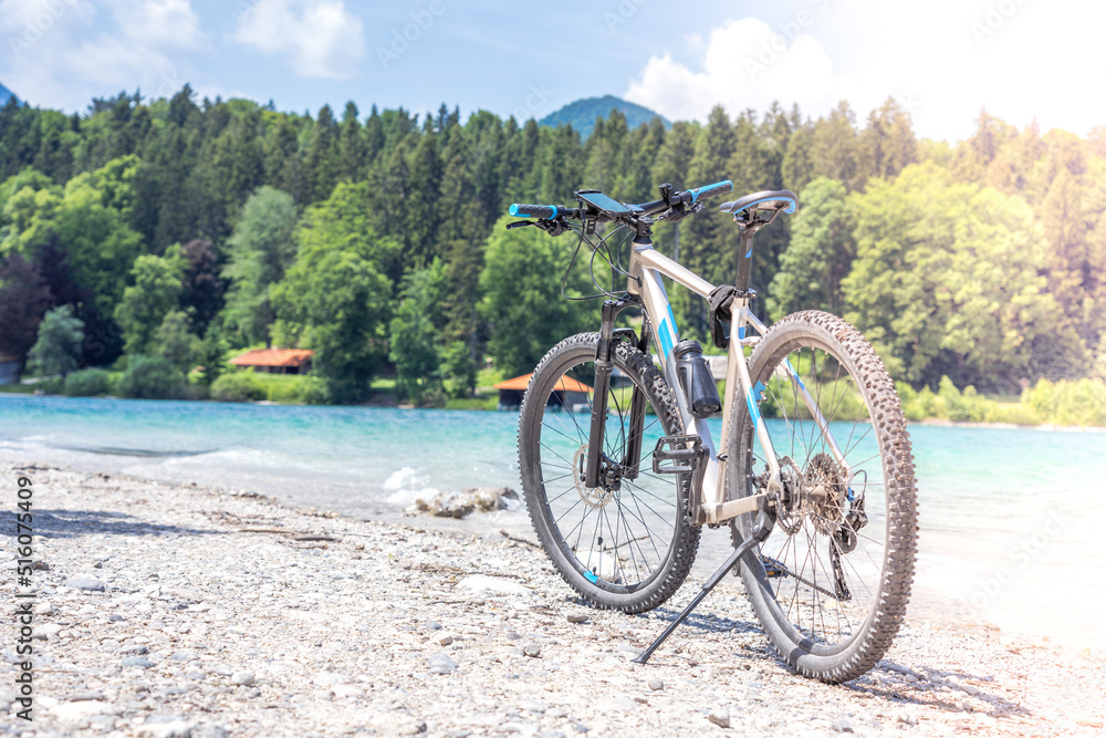 The bike stands against the backdrop of mountains and a lake