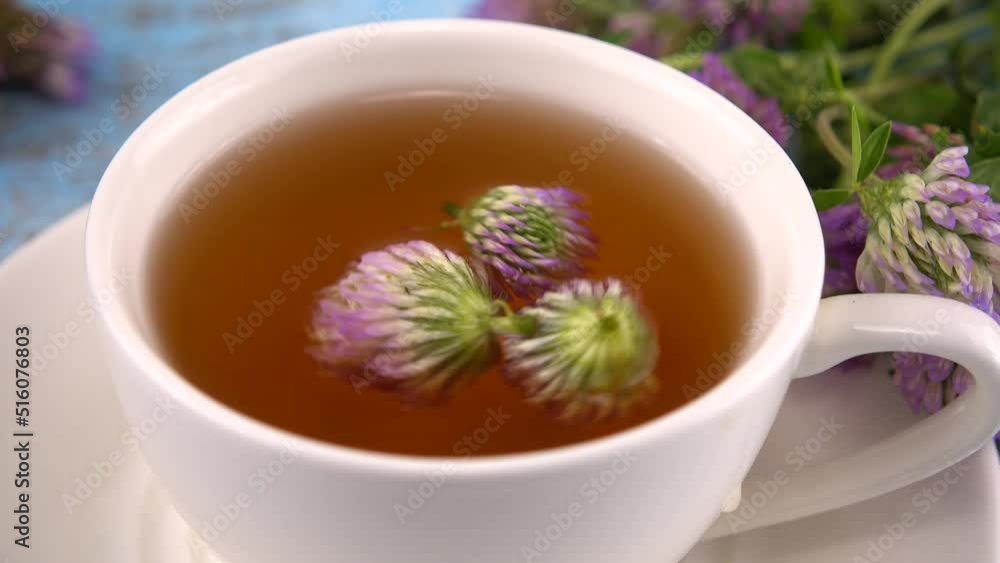 Brewing a tisanes from red clover in a white cup.
