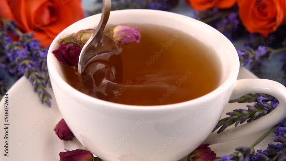 Provencal style composition: tea with fragrant rose buds, fresh rose flowers and lavender on a vintage light blue wooden tabletop. Slow motion. Provencal style composition: tea with fragrant rose buds, fresh rose flowers and lavender on a vintage light blue wooden tabletop. Slow motion.