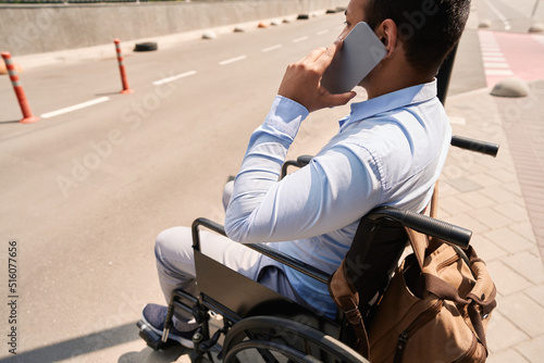 Wheelchair-bound person calling on mobile phone outdoors