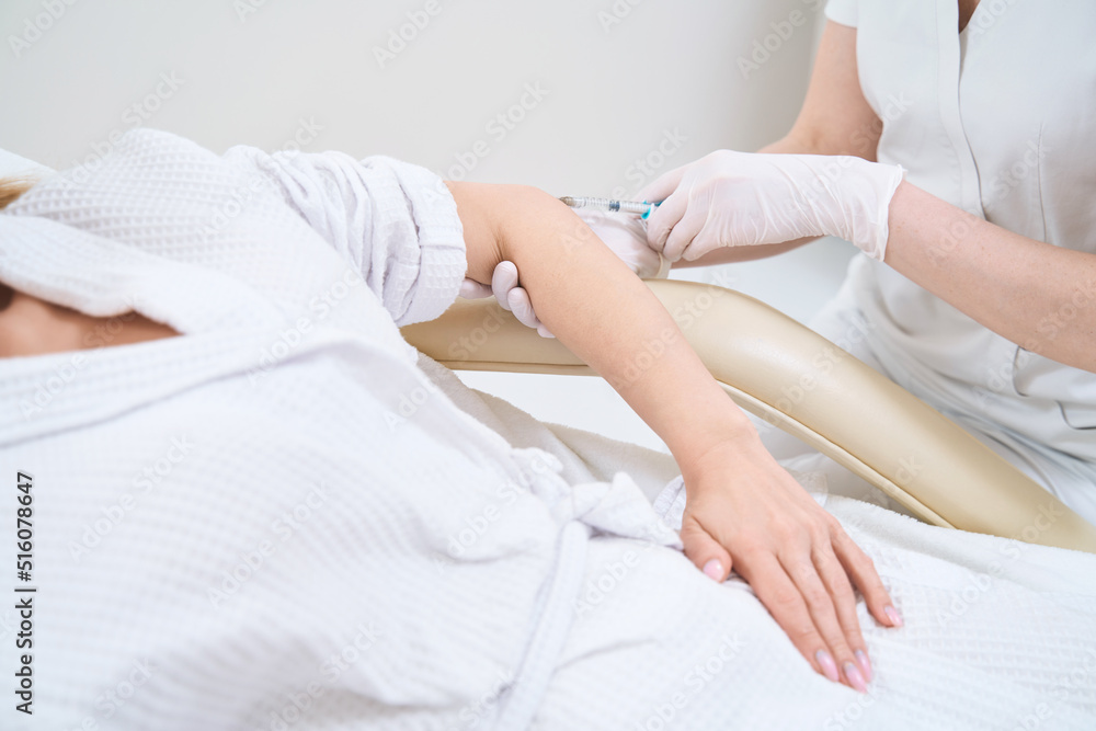 Medical worker gives an injection to a patient to tighten the skin of the elbow