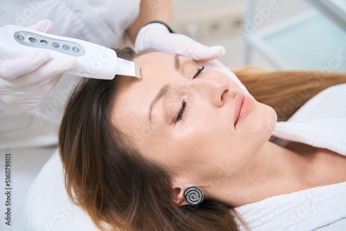 Woman in the cosmetology center on the procedure of ultrasonic facial cleansing