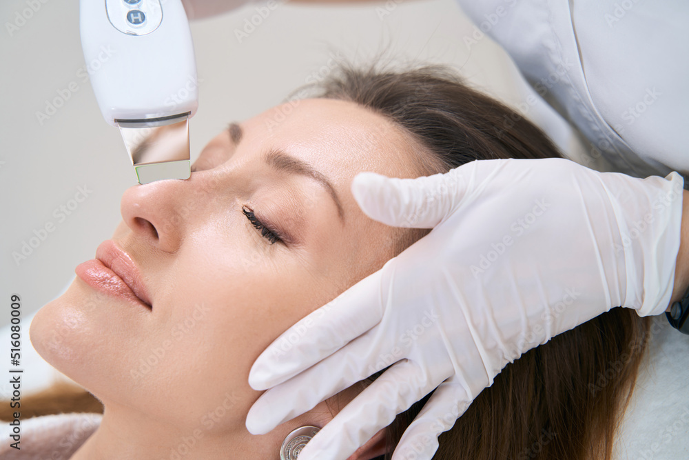 Naklejka premium Facial cleansing with an ultrasonic device for lady