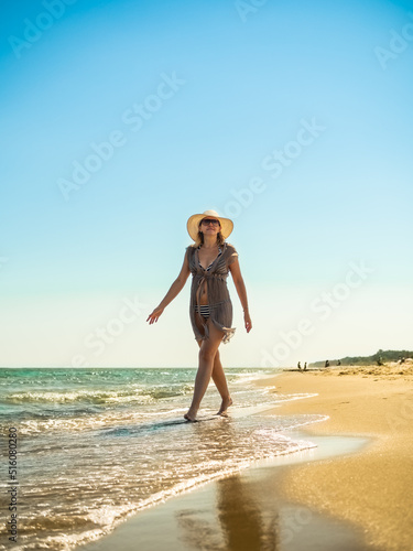 Woman walking on sunny beach
