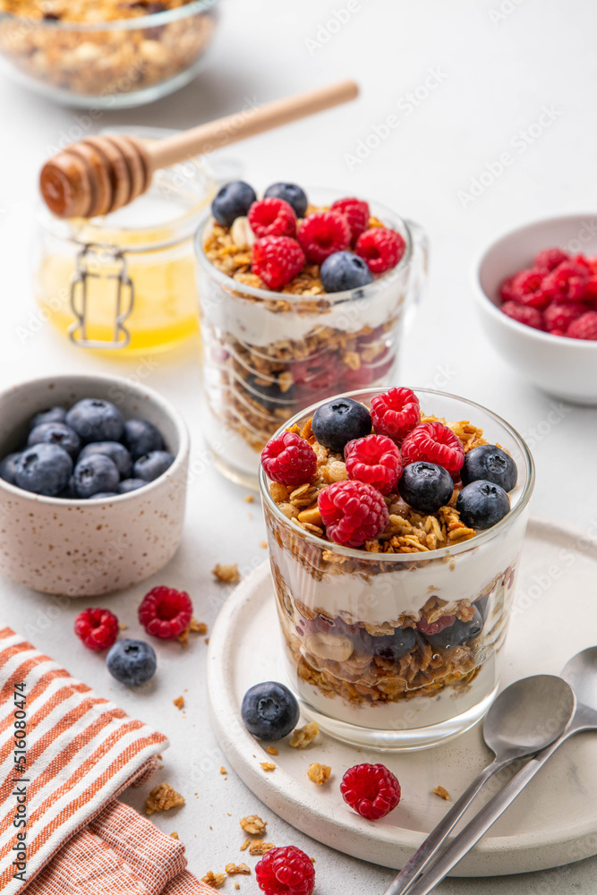 Granola with yogurt in glass served with fresh raspberry, blueberry and honey. Homemade oatmeal muesli. Vegetarian breakfast, healthy eating concept. Selective focus. Granola with yogurt in glass served with fresh raspberry, blueberry and honey. Homemade oatmeal muesli. Vegetarian breakfast, healthy eating concept. Selective focus.