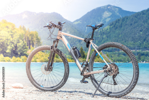 The bike stands against the backdrop of mountains and a lake