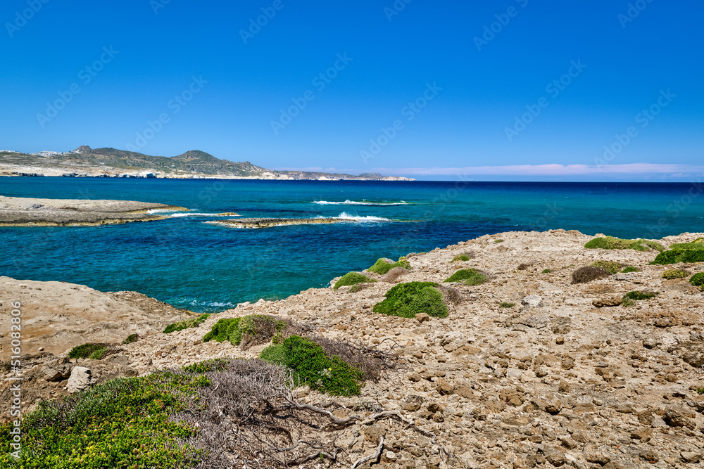 Typical beautiful view of Greek island landscape on sunny summer day. Blue sky, clouds, azure sea, rocky cliffs. Milos island, Greece Typical beautiful view of Greek island landscape on sunny summer day. Blue sky, clouds, azure sea, rocky cliffs. Milos island, Greece