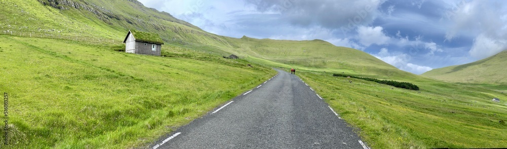 Straight road crossing the green field of Faroe Islands 