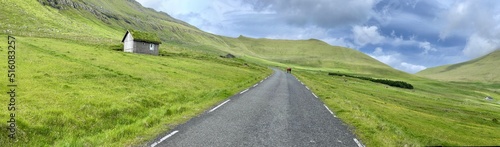 Straight road crossing the green field of Faroe Islands 