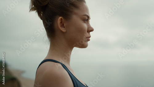 Sportswoman looking ahead standing beach closeup. Girl making breathing exercise