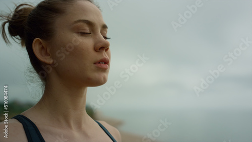Yogi woman making deep breath meditating on beach. Lady practicing yoga close up