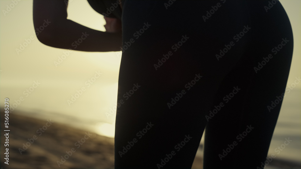 Silhouette woman stretching sunlight. Athletic girl practicing yoga on beach.