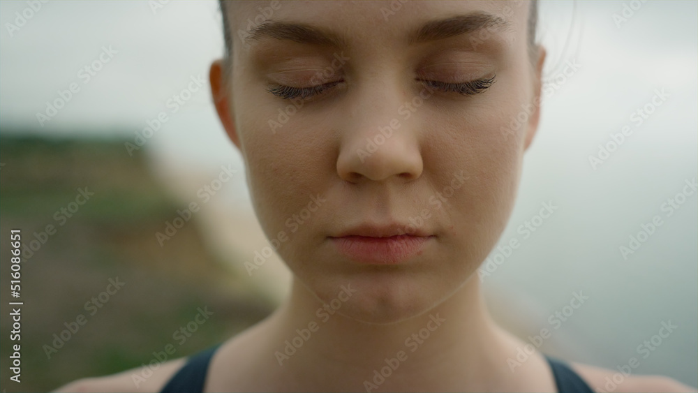 Girl take deep inhale with closed eyes meditating yoga on seashore close up. Girl take deep inhale with closed eyes meditating yoga on seashore close up.