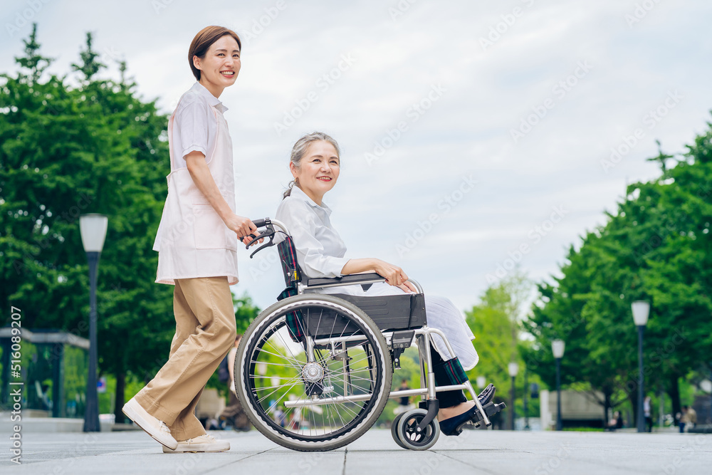A woman in a wheelchair and young woman in an apron to care for