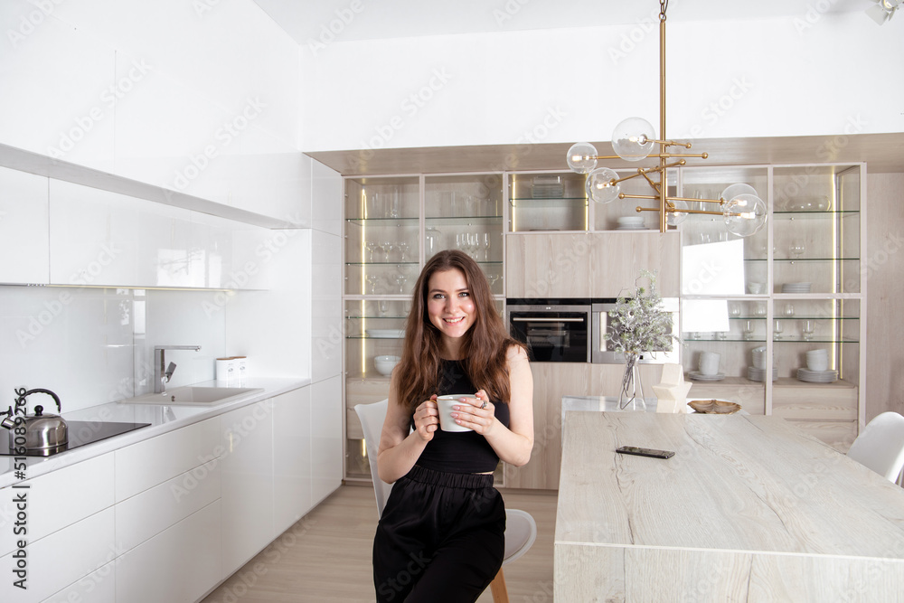 Young lonely brunette woman sitting in the kitchen with cup of tea
Young lonely brunette woman sitting in the kitchen with cup of tea