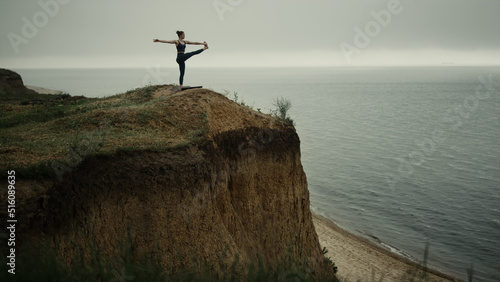 Graceful woman making yoga asana training balance on beach mound outdoor. 