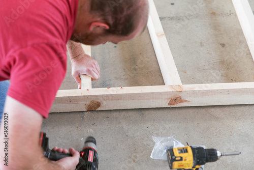 30s-40s man drilling wood frame on the floor