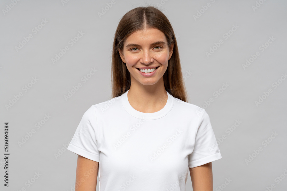 Young woman in casual white t-shirt standing isolated on gray background Young woman in casual white t-shirt standing isolated on gray background