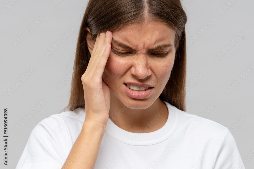 Young woman suffering from headache, isolated on gray background Young woman suffering from headache, isolated on gray background