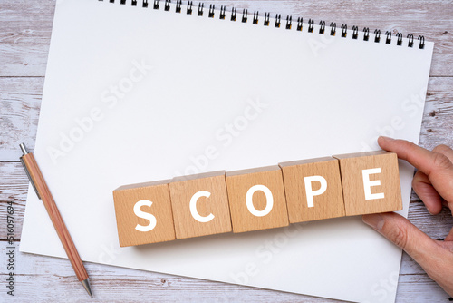 スコープ・範囲のイメージ｜「SCOPE」と書かれたブロック、ノート、ペン、手 