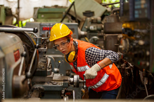 Professional young White female industry engineer worker works in safety uniform with metalwork precision tools, mechanical lathe machines, and spare parts workshop in the steel manufacturing factory.
