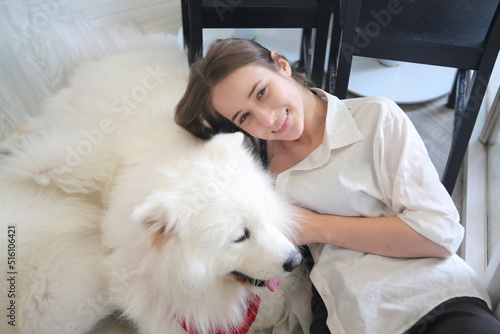Smiling young attractive woman embracing cute puppy dog border collie on floor. Girl hugging new lovely member of family. Pet care and animals concept © FotoArtist