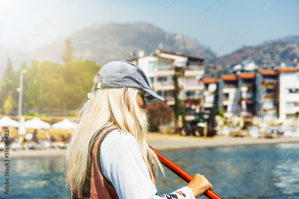 Girl on the SUP board on the background of the city beach. Active lifestyle concept