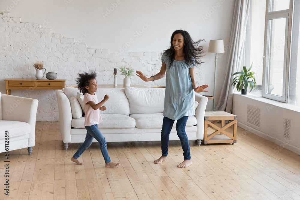 African mom and active preschool 5s daughter dance together barefoot on ...