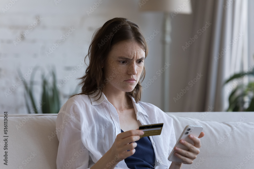 Young woman hold credit card and smartphone try pay via e-bank application experiences problem, feels annoyed. Lack of money, insecure unsuccessful payment, fraud, insufficient funds for e-pay concept Young woman hold credit card and smartphone try pay via e-bank application experiences problem, feels annoyed. Lack of money, insecure unsuccessful payment, fraud, insufficient funds for e-pay concept
