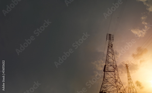 Power plant silhouette At sunset, a high-voltage tower stands against the sky. Electrical transmission wires from the bottom.