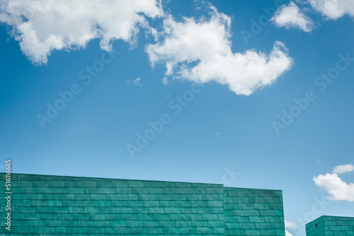 un bâtiment bleu devant un ciel bleu avec des nuages blancs. Détail d'un building moderne sous un ciel bleu d'été.