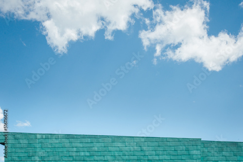 un bâtiment bleu devant un ciel bleu avec des nuages blancs. Détail d'un building moderne sous un ciel bleu d'été.