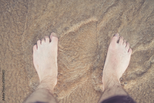 Feet standing in the ocean water