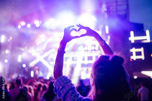 Heart shaped hands at concert, loving the artist and the festival. Music concert with lights and silhouette of people enjoying the concert. photo