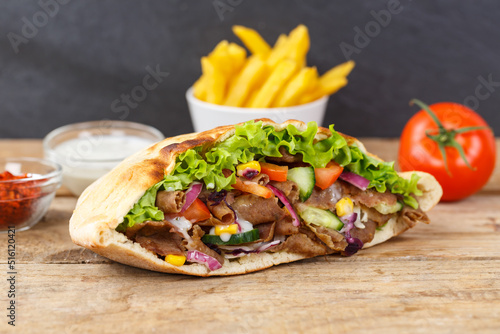 Döner Kebab Doner Kebap fast food meal in flatbread with fries on a wooden board