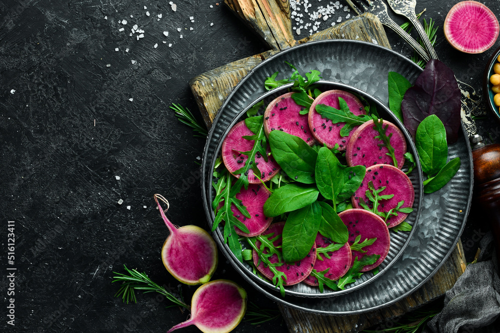 Vegetable diet salad: spinach, watermelon radish, black sesame and olive oil. Vegan food. Top view. On a stone background. Vegetable diet salad: spinach, watermelon radish, black sesame and olive oil. Vegan food. Top view. On a stone background.