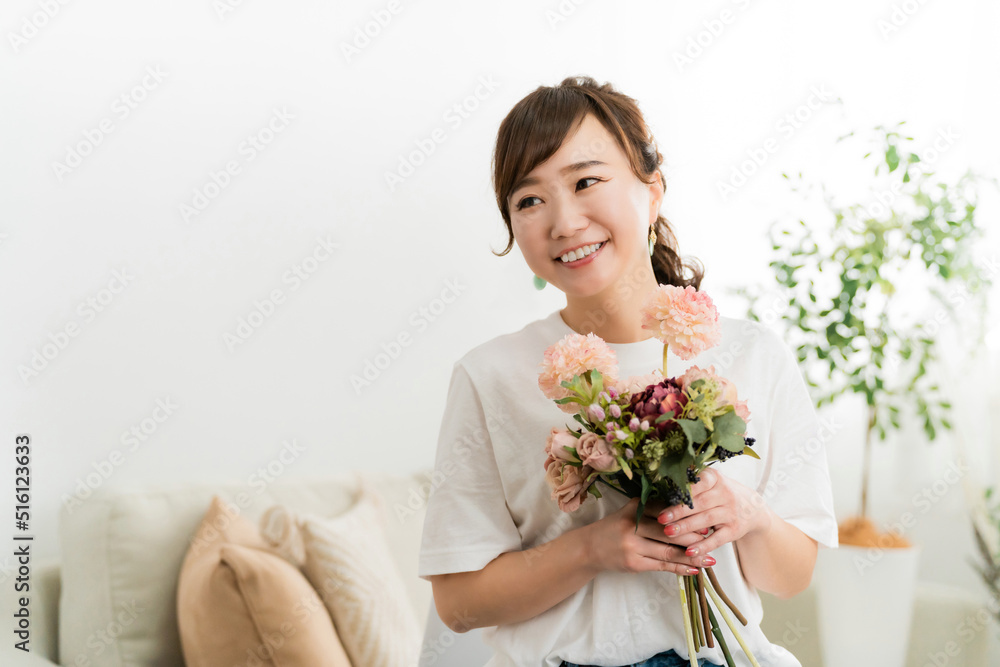 家のソファで花束を持つ日本人女性（母の日・誕生日・結婚記念日）
