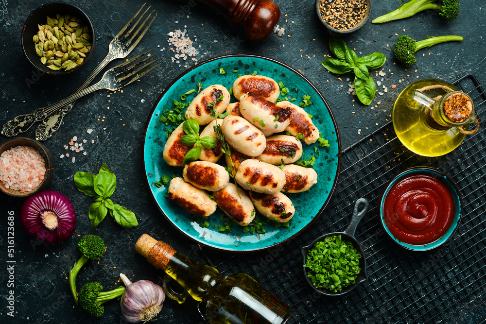 Grilled sausages with rosemary and spices on a plate. Barbecue. Meat menu. Top view. On a stone background.