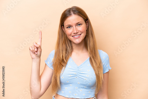 Young caucasian woman isolated on beige background pointing up a great idea