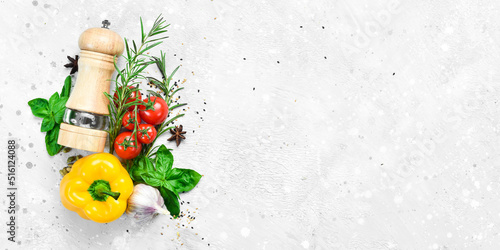 Fototapeta Naklejka Na Ścianę i Meble -  Food background. Vegetables, spices and pepper mill on a gray stone background. Top view. Free space for text.
