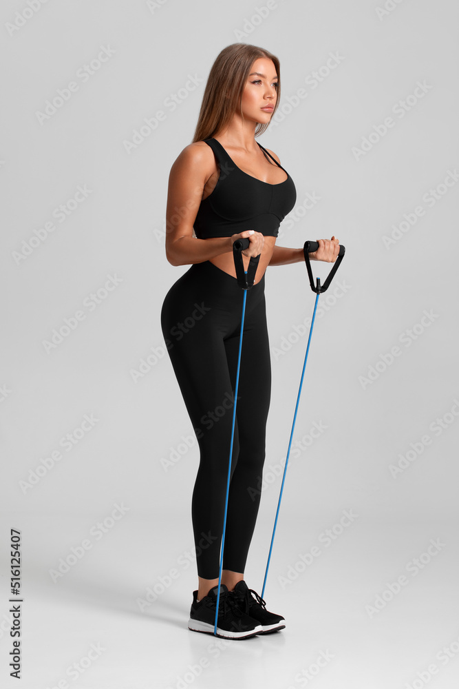 Fitness woman working out with resistance band on gray background. Athletic girl exercises with expander Fitness woman working out with resistance band on gray background. Athletic girl exercises with expander