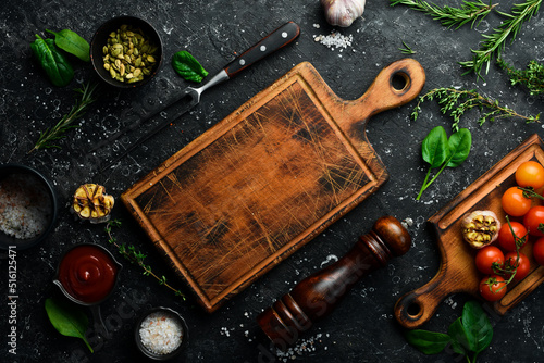 Kitchen board on black stone cooking background. Fresh vegetables and spices on a stone table. Top view.