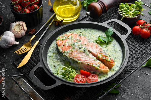 Salmon steak with creamy spinach sauce in a pan. Restaurant food. Seafood. Rustic style. Flat Lay.