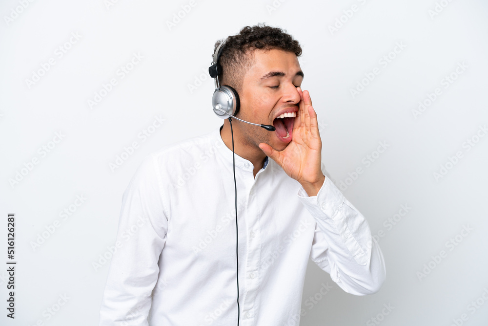 Telemarketer Brazilian man working with a headset isolated on white background shouting with mouth wide open to the lateral Telemarketer Brazilian man working with a headset isolated on white background shouting with mouth wide open to the lateral